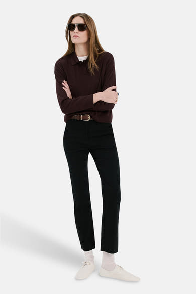 Pull col rond bordeaux de MANGO, porté avec un pantalon noir, une ceinture marron et des lunettes de soleil.