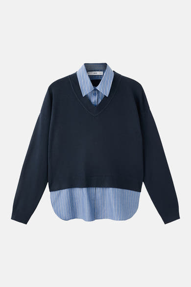 MANGO blauwe V-hals trui, gedragen over een blauw-wit gestreept overhemd.