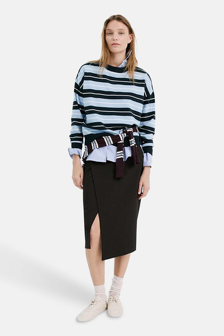 Pull col rond multicolore de MANGO, à rayures bleues, blanches et noires, porté avec une jupe noire fendue.