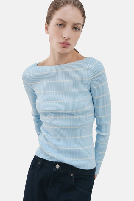 Pull à col rond multicolore de MANGO, rayures horizontales blanches sur fond bleu clair, porté avec un jean foncé.
