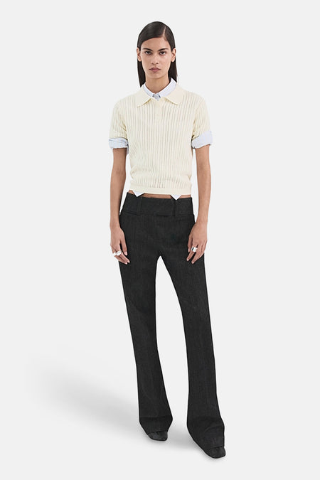 Polo beige en maille côtelée de MANGO, porté avec une chemise blanche à manches courtes et un pantalon noir taille basse.