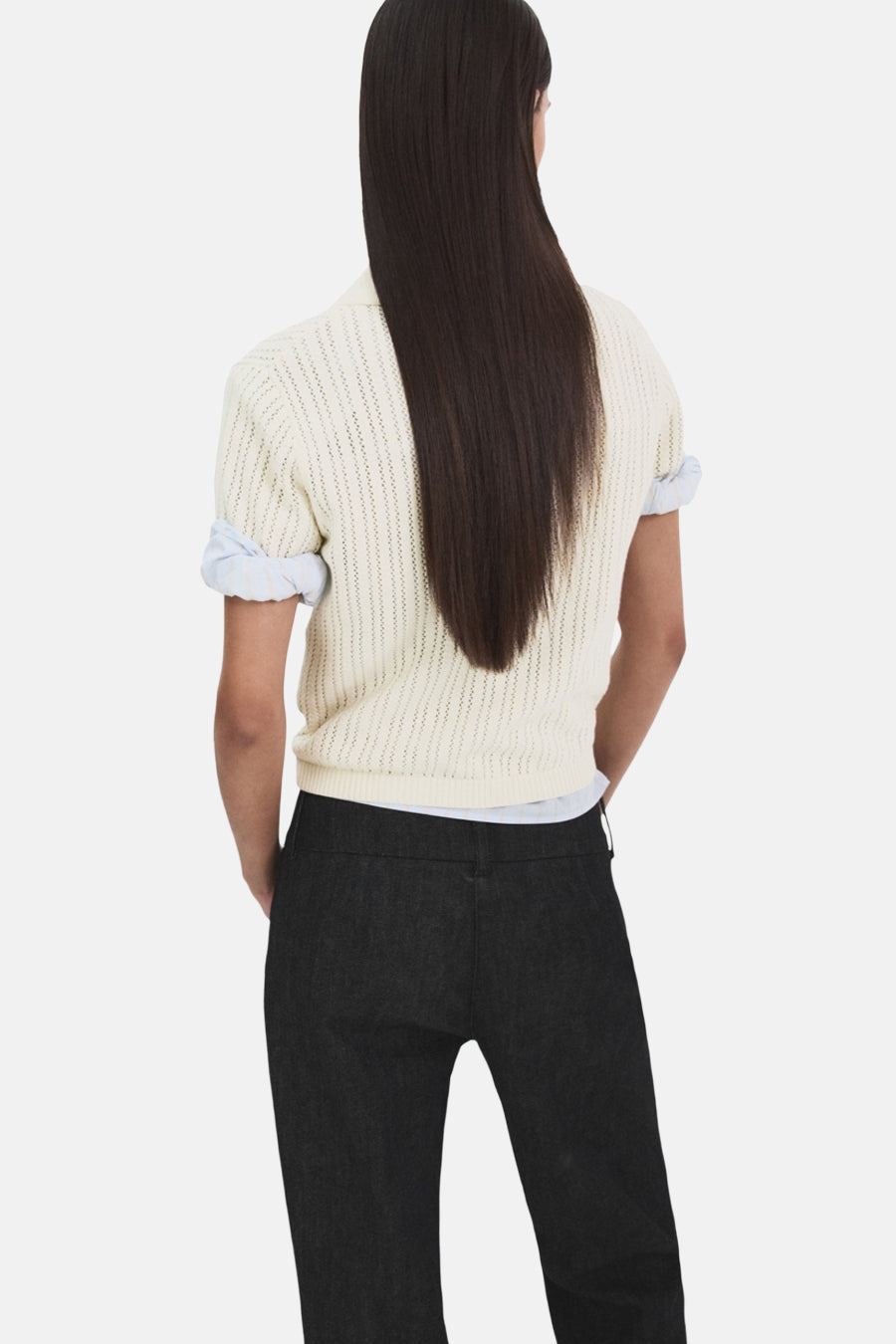 Polo beige de MANGO, porté avec un t-shirt clair et un pantalon sombre uni, vue de dos.