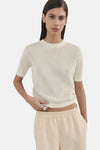 Ecru ronde hals trui van MANGO met opengebreide textuur, gedragen met een wijde beige broek.