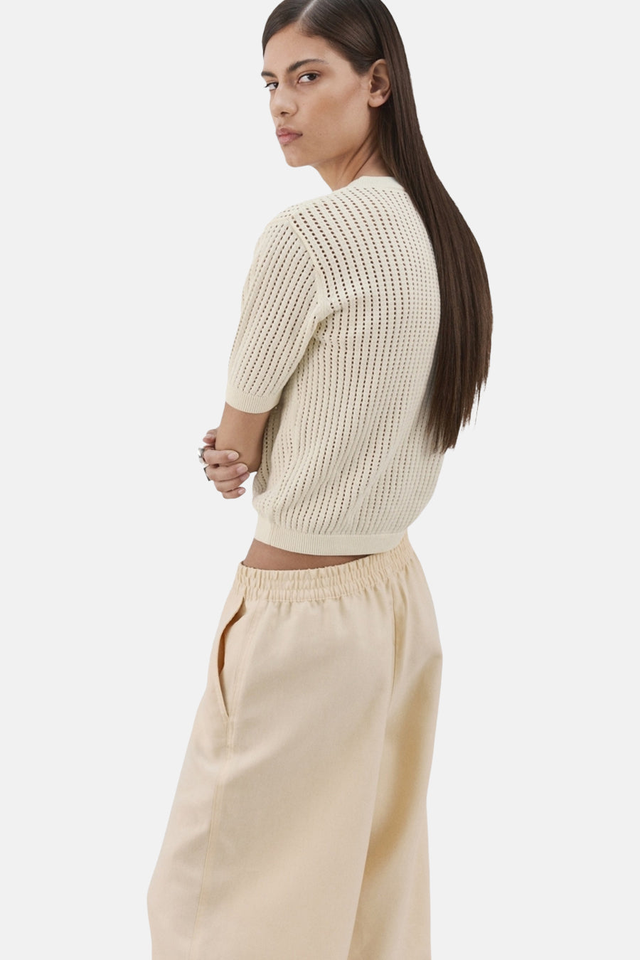 Pull à col rond écru de MANGO avec texture ajourée, porté avec un pantalon beige ample.