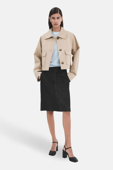 Blauwe trui met ronde hals van MANGO, gedragen met een beige jas met zakken en een zwarte kokerrok.