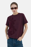 Bordeaux T-shirt met korte mouwen van MANGO, gedragen met een wijde blauwe jeans en een zonnebril.