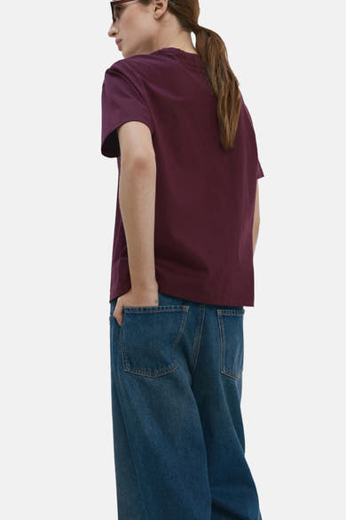 T-shirt bordeaux à manches courtes de MANGO, porté avec un jean bleu ample et des lunettes de soleil.