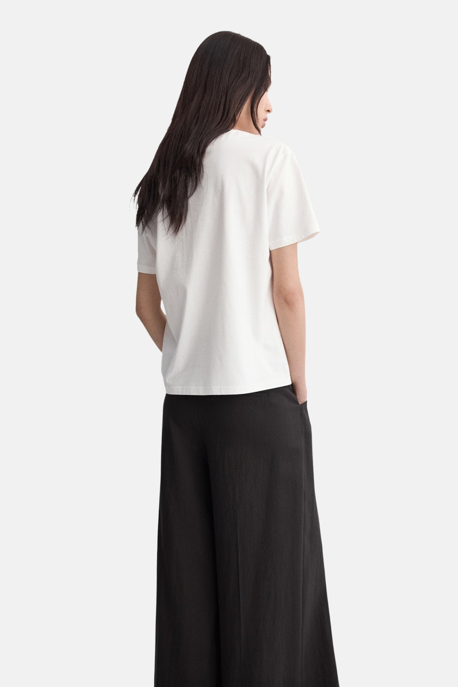 T-shirt blanc à manches courtes de MANGO, avec une coupe décontractée porté avec un pantalon noir ample.
