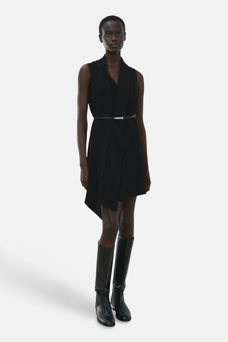 Robe noire cintrée à la taille par MANGO, portée avec des bottes hautes en cuir noir.
