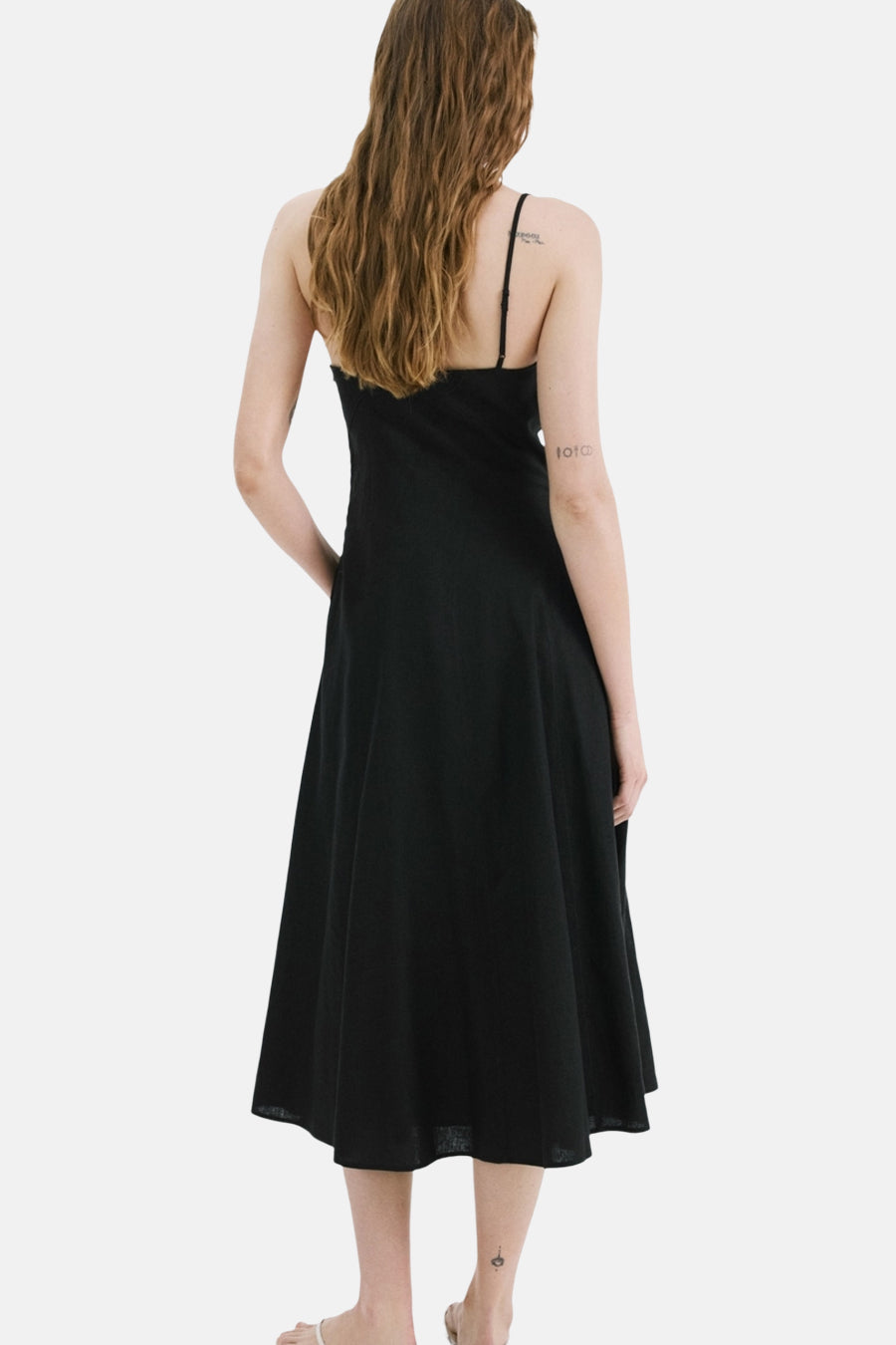 Robe noire de MANGO, avec fines bretelles et coupe mi-longue évasée, vue de dos.