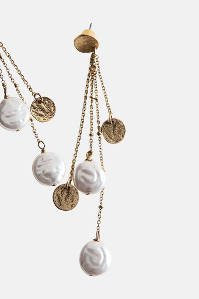 Boucles d'oreilles dorées par MANGO avec perles blanches et chaînes pendantes texturées.