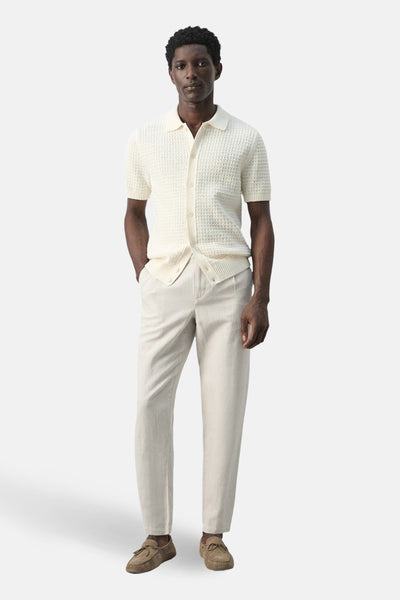 Pantalon écru de MANGO, associé à un cardigan en maille ajourée et des mocassins marron.