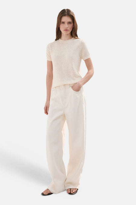 Beige fijngebreide pull met korte mouwen van MANGO, gedragen met een crèmekleurige wijde broek en sandalen.