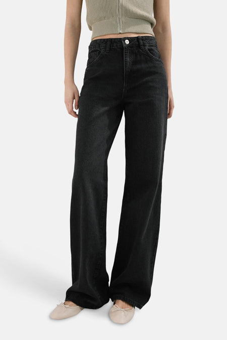 Jean droit en denim gris foncé de MANGO, porté avec un top court tricoté et des ballerines beige.
