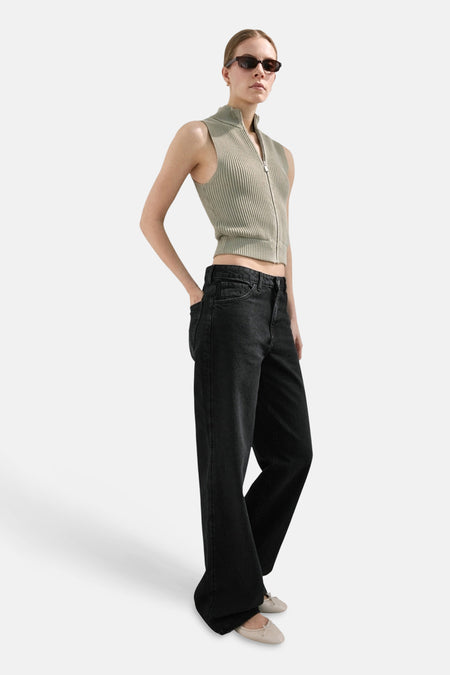 Jean droit gris foncé de MANGO, porté avec un haut sans manches vert et des ballerines beiges.
