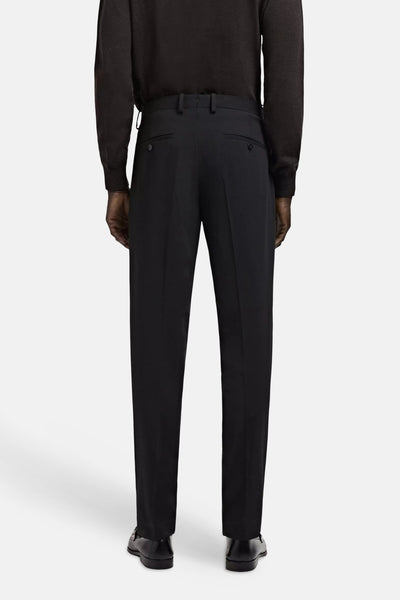 Black tailored suit pants with pleated front, back view, worn with dark sweater and black dress shoes