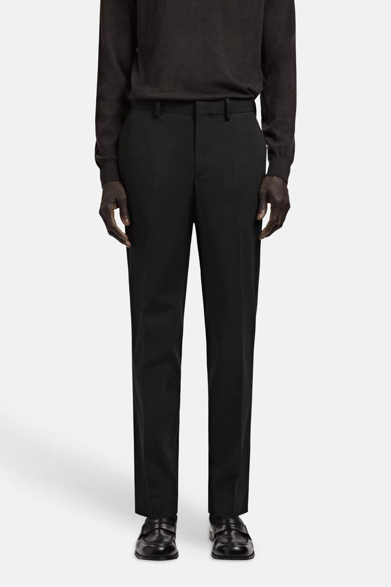 Black tailored suit pants with front pleats, worn with dark long-sleeve top and black loafers, front view