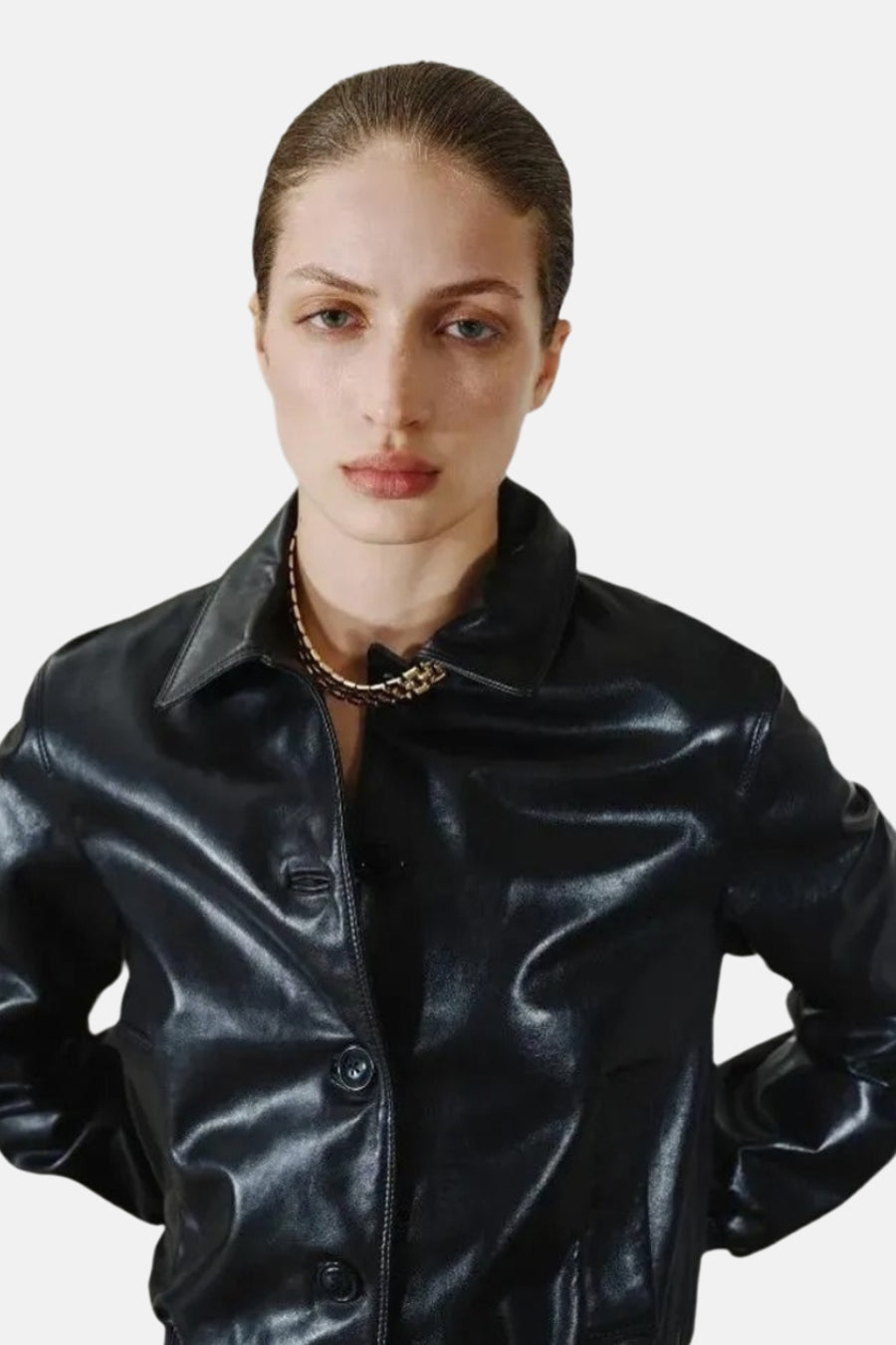 Korte gouden halsketting van MANGO, gouden ketting met contrasterende schakels, gedragen met een zwarte lederen jas.