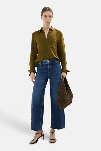 Jean large bleu moyen de MANGO, porté avec une chemise vert olive et des sandales à talons noirs.