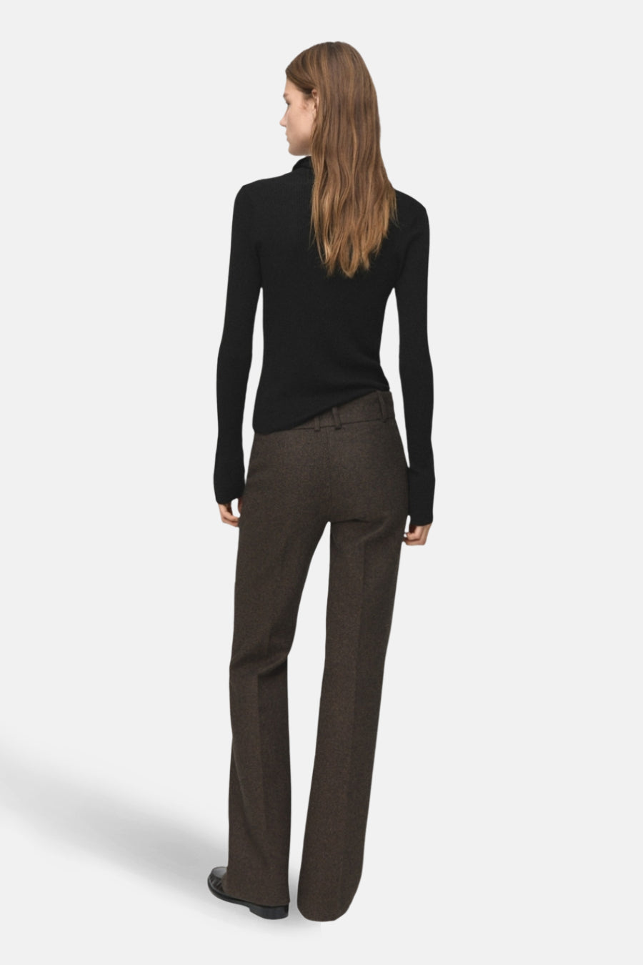Pull à col rond noir de MANGO, à manches longues, porté avec un pantalon brun à jambes larges.