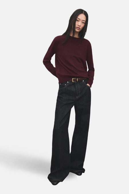 Pull à col rond bordeaux de MANGO, porté avec un jean taille haute et une ceinture marron.