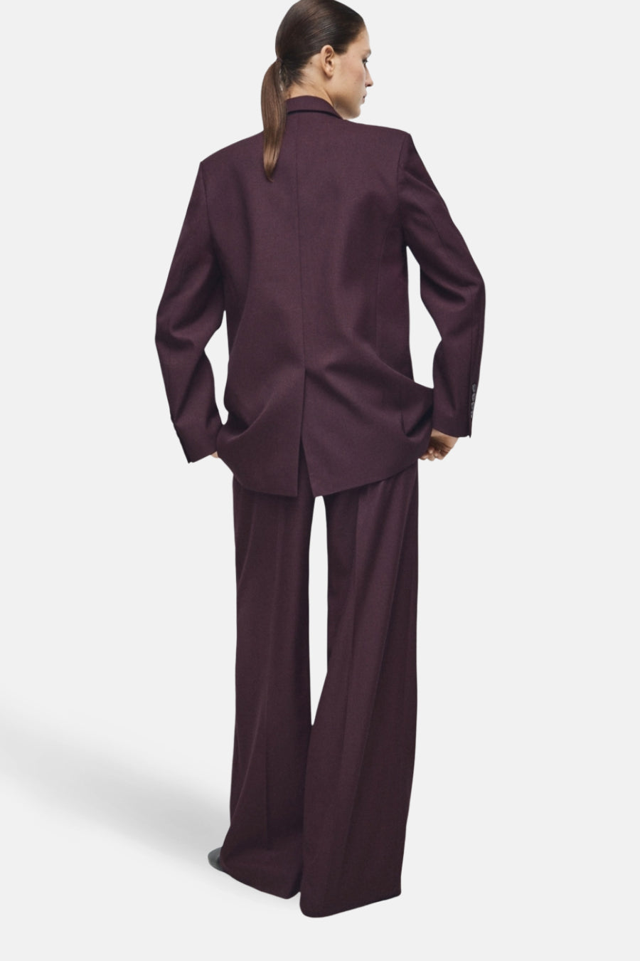 Pantalon de costume bordeaux de MANGO, coupe ample et jambes larges, porté avec une veste assortie.