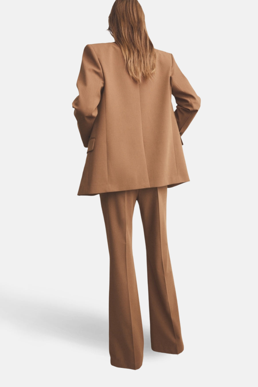 Pantalon brun de MANGO, coupe évasée, vu de dos avec un blazer coordonné.
