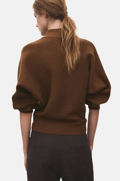 Pull à col roulé brun de MANGO, manches bouffantes, porté avec un pantalon à carreaux marron, vue de dos.
