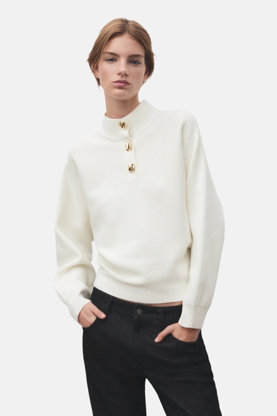 Pull à col roulé écru de MANGO, avec trois boutons dorés, porté avec un jean noir.
