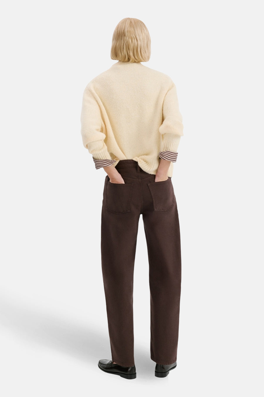 Jean coloré brun par MANGO, avec poches et coupe droite, porté avec un pull crème et des chaussures noires.
