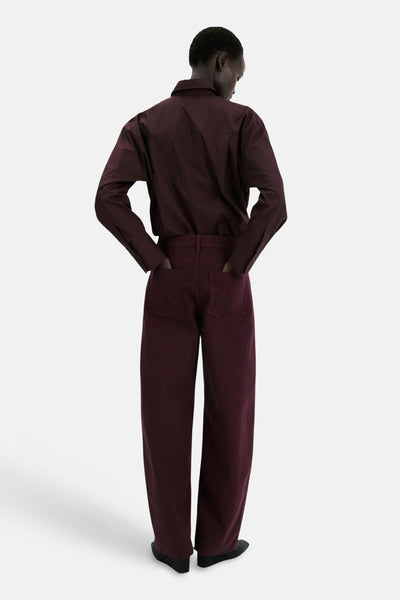 Jean coloré bordeaux de MANGO, coupe ample, avec les mains dans les poches arrière et chaussures noires.
