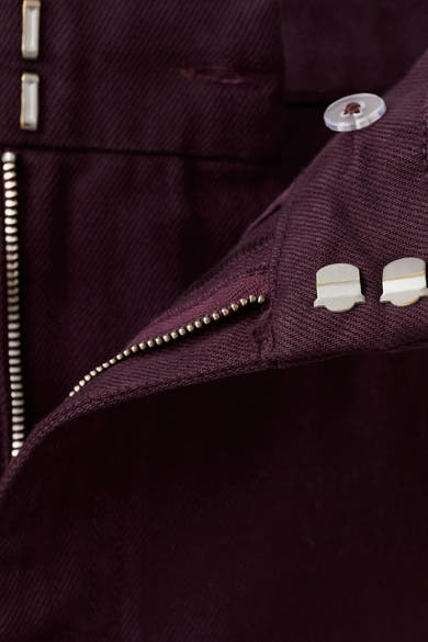 Jeans coloré bordeaux de MANGO, avec fermeture éclair et des boutons argentés.