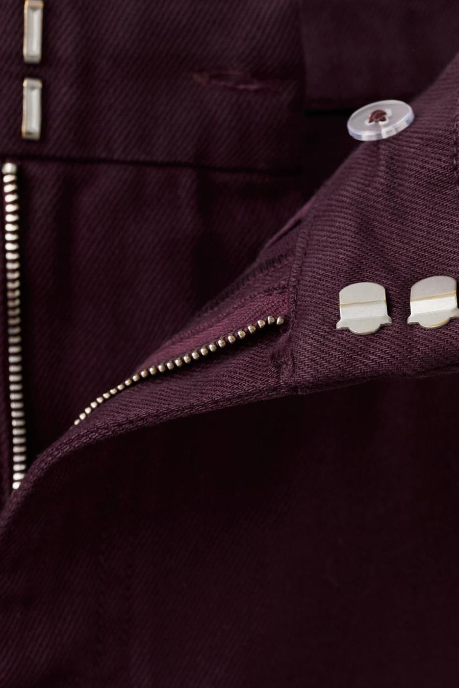 Jeans coloré bordeaux de MANGO, avec fermeture éclair et des boutons argentés.
