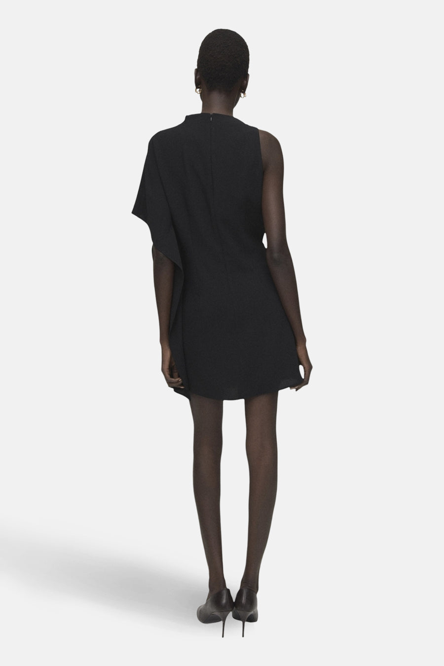 Robe noire asymétrique de MANGO, avec une épaule dénudée et coupe mini, vue de dos.