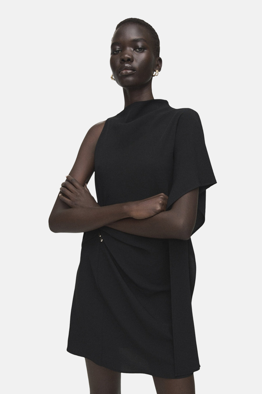 Zwarte jurk van MANGO met blote schouder, asymmetrische snit en gedrapeerde details.