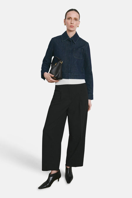 Pantalon noir de MANGO, coupe ample et jambes larges, porté avec un veste en denim et des bottines en cuir.