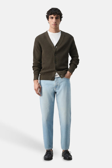Gilet brun de MANGO, porté sur un t-shirt blanc avec un jean bleu clair, boutonné, avec texture gaufrée.
