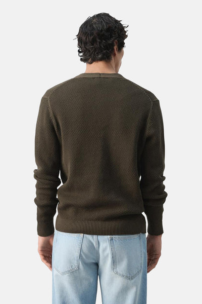 Gilet brun de MANGO, texture nid d'abeille, porté avec un jean bleu clair, vue de dos.