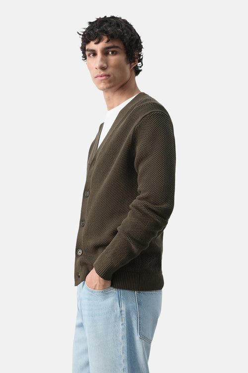 Gilet marron de MANGO, en maille texturée, porté sur un t-shirt blanc et un jean bleu clair, vue de côté.