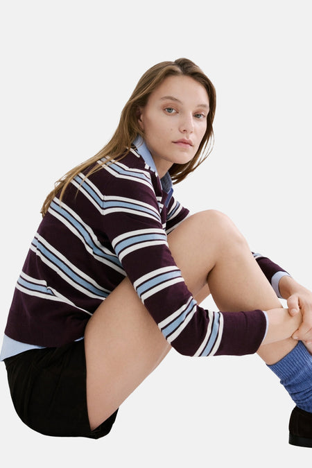 Pull col rond multicolore de MANGO, à rayures bordeaux, blanches et bleues, porté avec un short noir et des chaussettes bleues.
