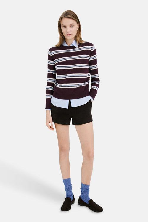 Pull ras du cou multicolore de MANGO, porté avec une chemise bleue et un short noir.