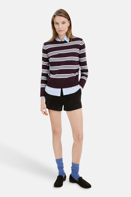 Pull ras du cou multicolore de MANGO, porté avec une chemise bleue et un short noir.