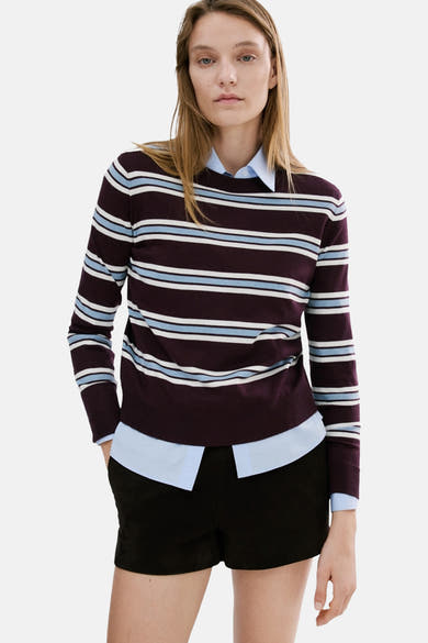 MANGO ronde hals meerkleurige trui, met blauwe en witte horizontale strepen, gedragen over een blauw overhemd en een zwarte korte broek.