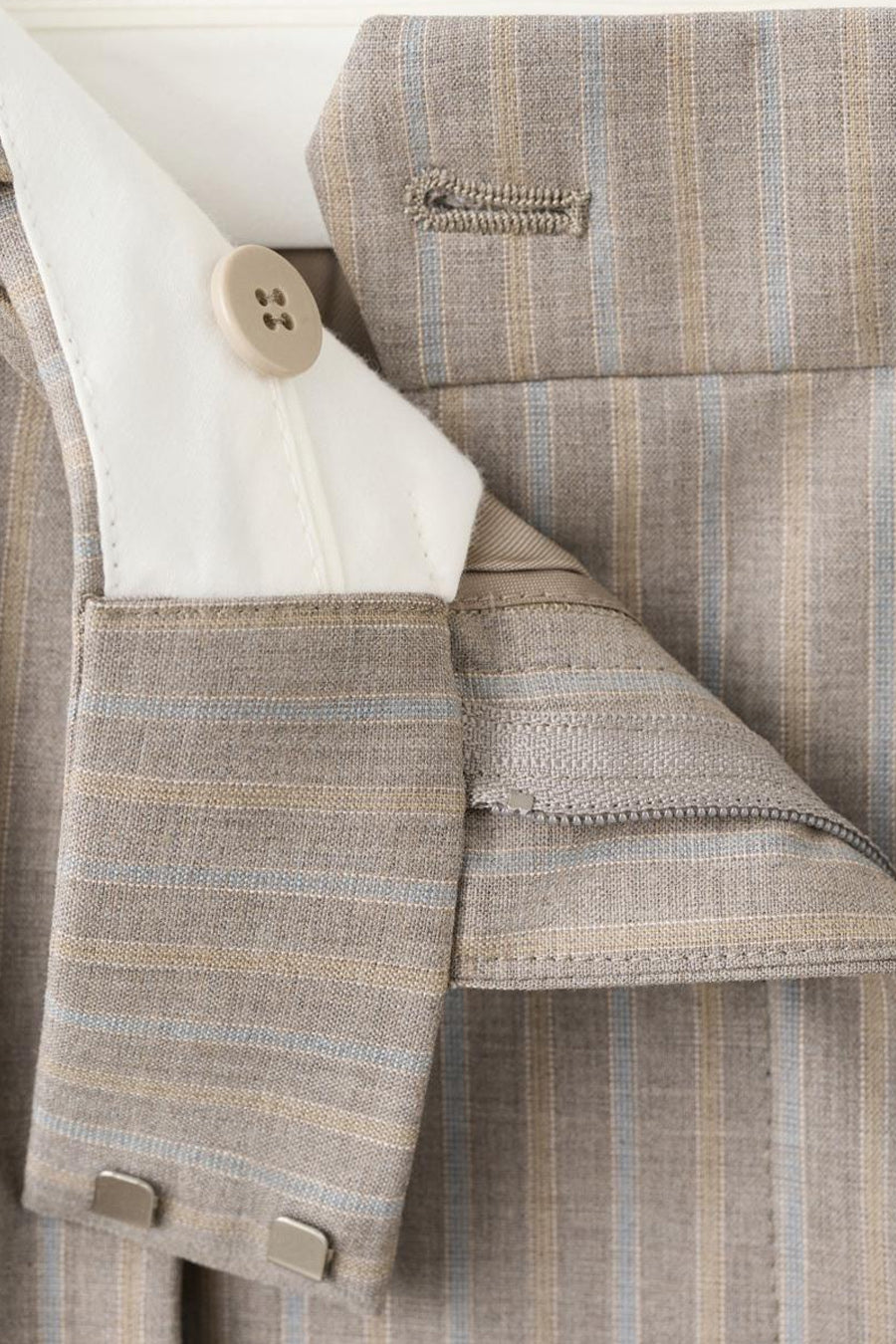 Pantalon de costume brun par MANGO, à rayures fines beiges et bleues, avec fermeture à bouton et agrafe.
