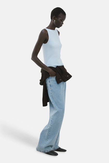 Top sans manches bleu de MANGO, porté avec un jean ample, veste marron à la taille, vue de côté.
