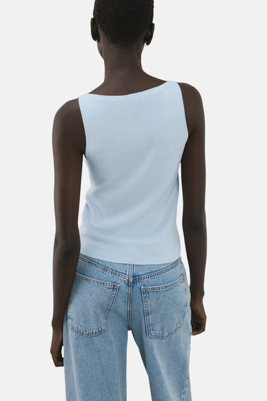 Top bleu clair de MANGO, coupe carrée au dos, porté avec un jean taille haute.

