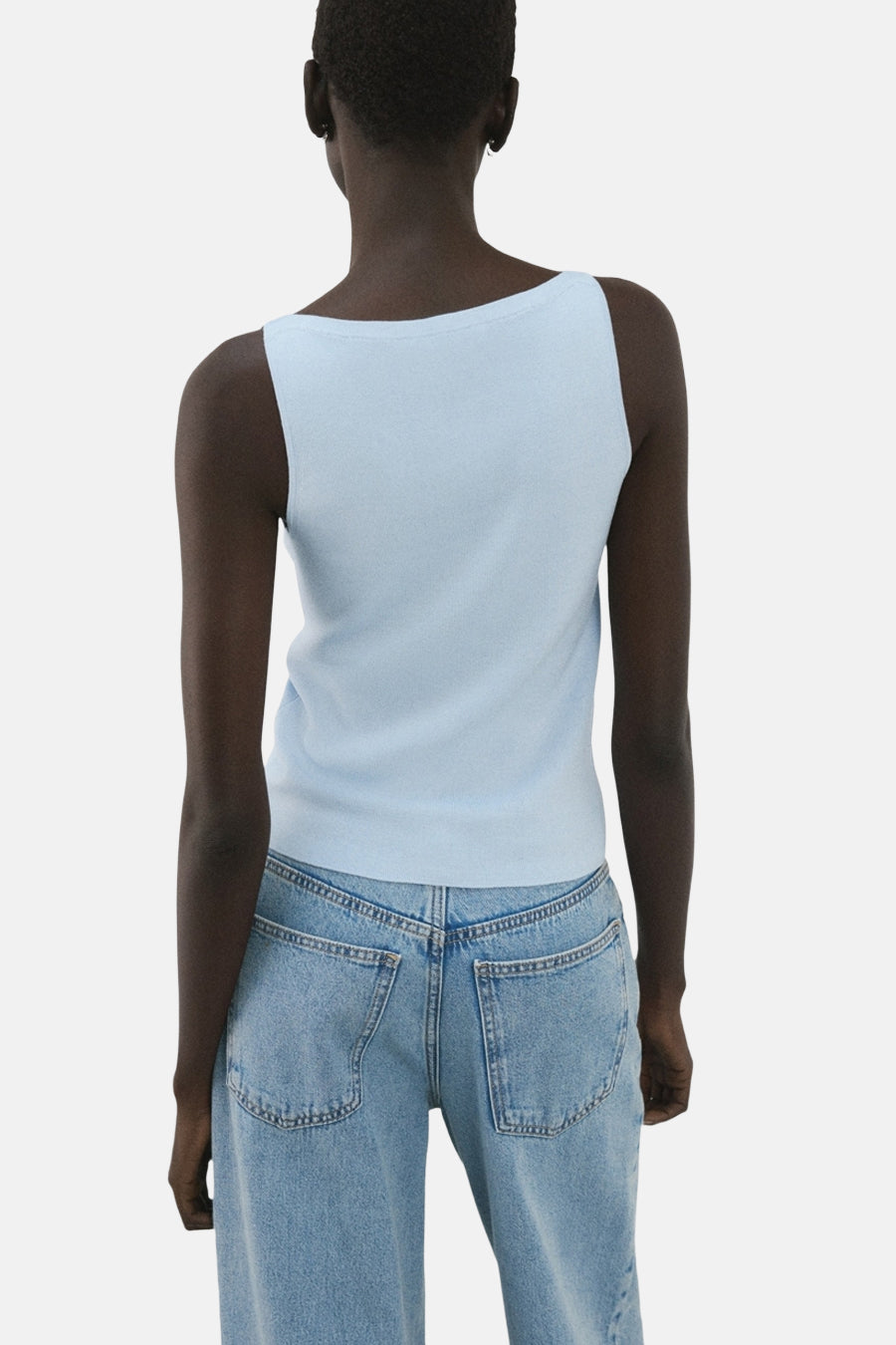 Top bleu clair de MANGO, coupe carrée au dos, porté avec un jean taille haute.
