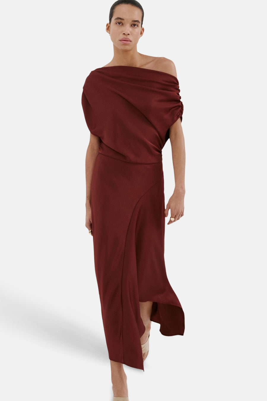 Bordeauxrode jurk van MANGO, gedrapeerd over één schouder, met een asymmetrische split, gedragen met nude pumps.