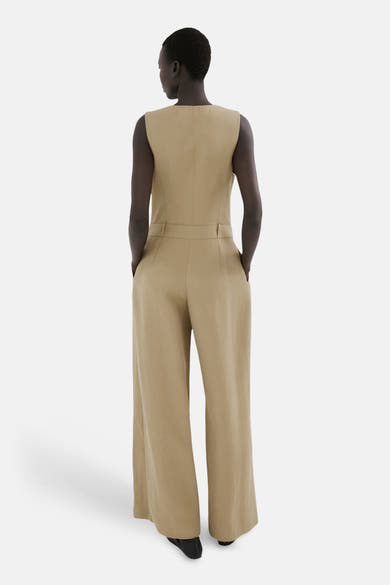Kaki overall van MANGO, met een wijde pasvorm en zijzakken, van achteren gezien.