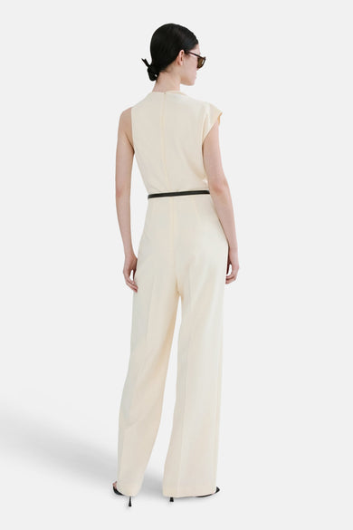 Ecru jumpsuit van MANGO, met dunne zwarte riem en wijde pijpen, van achteren gezien.